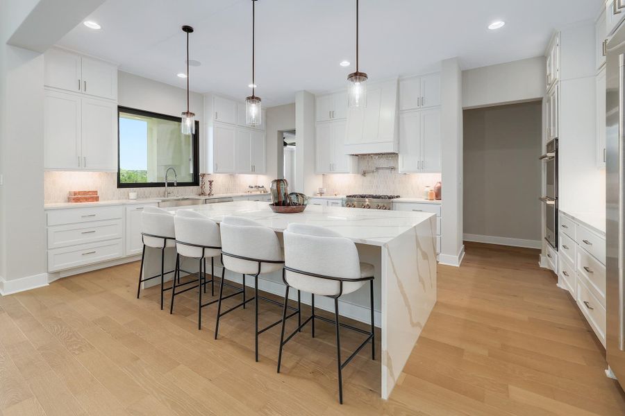 Culinary aspirations meet elegant design in this luminous kitchen featuring a waterfall island.