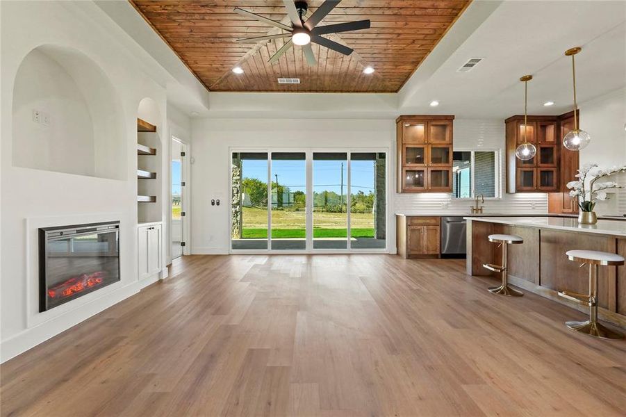 Kitchen featuring wooden ceiling, brown cabinetry, glass insert cabinets, recessed lighting, and a glass covered fireplace Kitchen featuring wooden ceiling, brown cabinetry, glass insert cabinets, recessed lighting, and a glass covered fireplace