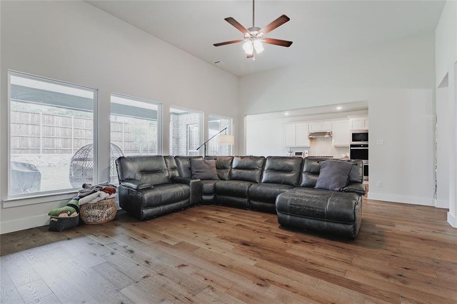 Spacious living area featuring wood-finish flooring, vaulted ceilings, and a ceiling fan