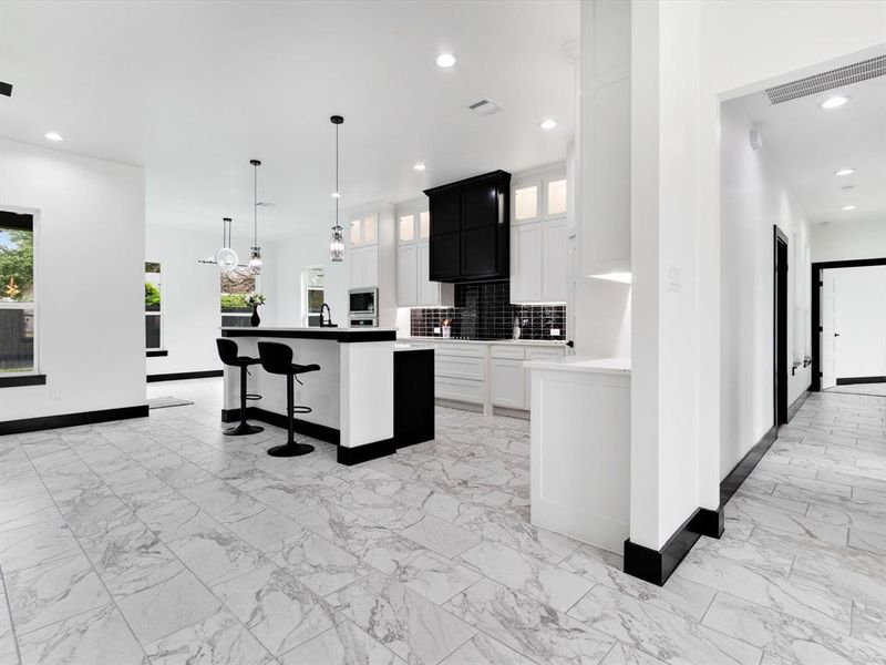 Kitchen featuring white cabinetry, black vent hood, and dark subway tile backsplash