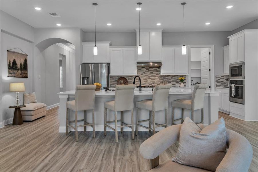 Kitchen featuring a breakfast bar area, tasteful backsplash, stainless steel appliances, a center island with sink, and recessed lighting Kitchen featuring a breakfast bar area, tasteful backsplash, stainless steel appliances, a center island with sink, and recessed lighting