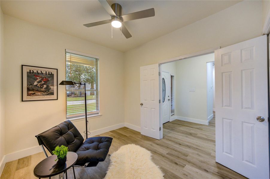 Cozy den with natural light, sleek flooring, and a modern ceiling fan — perfect for relaxation or work.