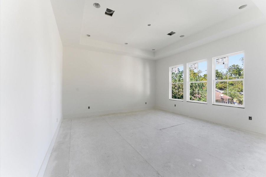 Primary bedroom is enhanced by natural light and a tray ceiling, which contributes to its architectural style. Primary bedroom is enhanced by natural light and a tray ceiling, which contributes to its architectural style.