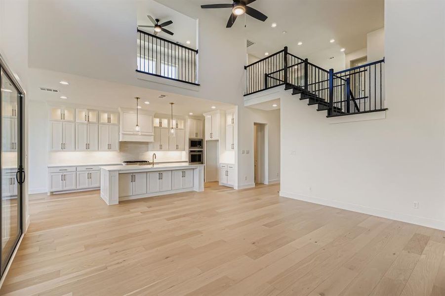 Kitchen featuring white cabinets, open floor plan, recessed lighting, a center island with sink, and light wood-style flooring