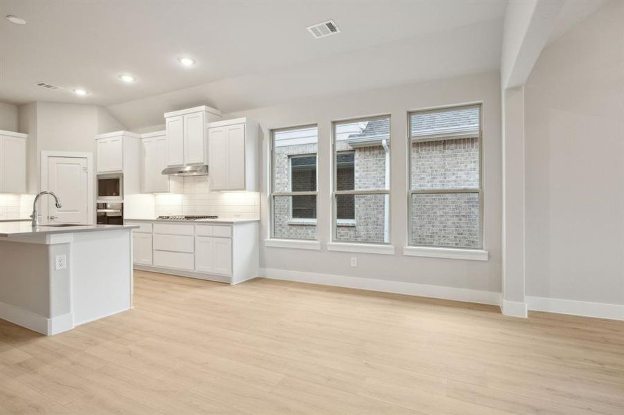 Kitchen featuring stainless steel gas cooktop, sink, white cabinets, and wall oven