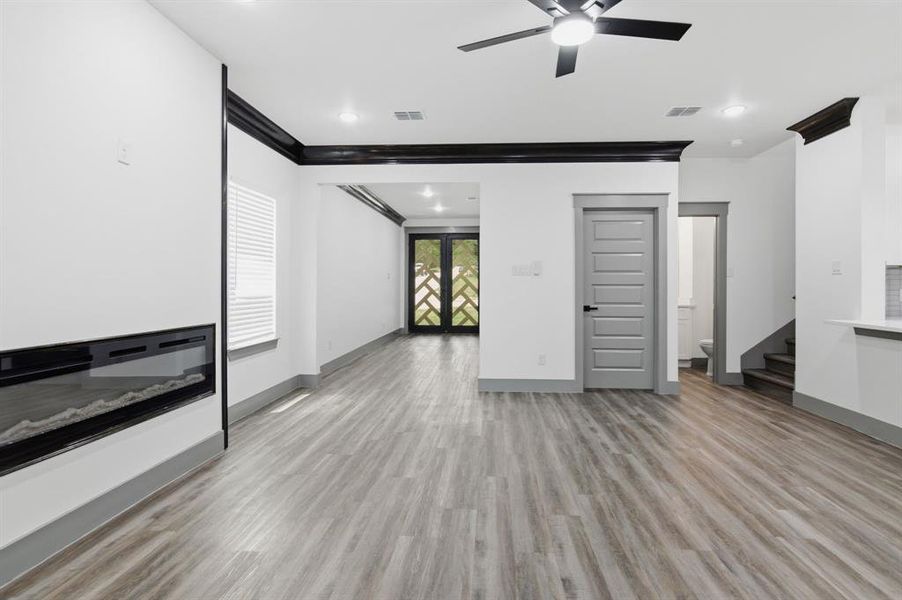 Spacious interior featuring wood-finish flooring, a contemporary linear fireplace, and a ceiling fan with integrated lighting