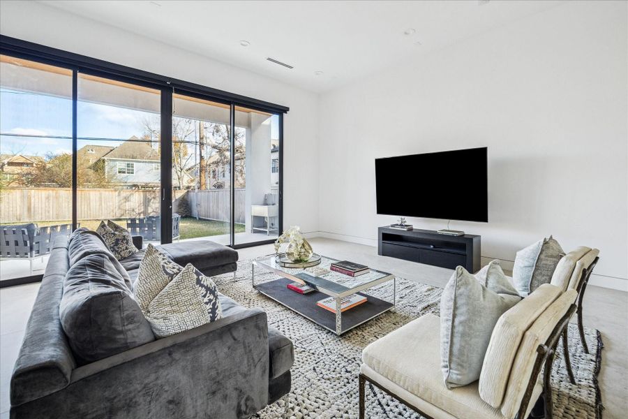 The living room is full of natural light with oversized sliding glass doors and automatic shades.