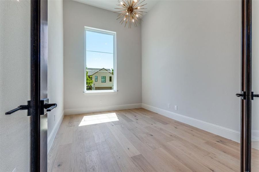 Spare room with light wood-style flooring and a chandelier Spare room with light wood-style flooring and a chandelier