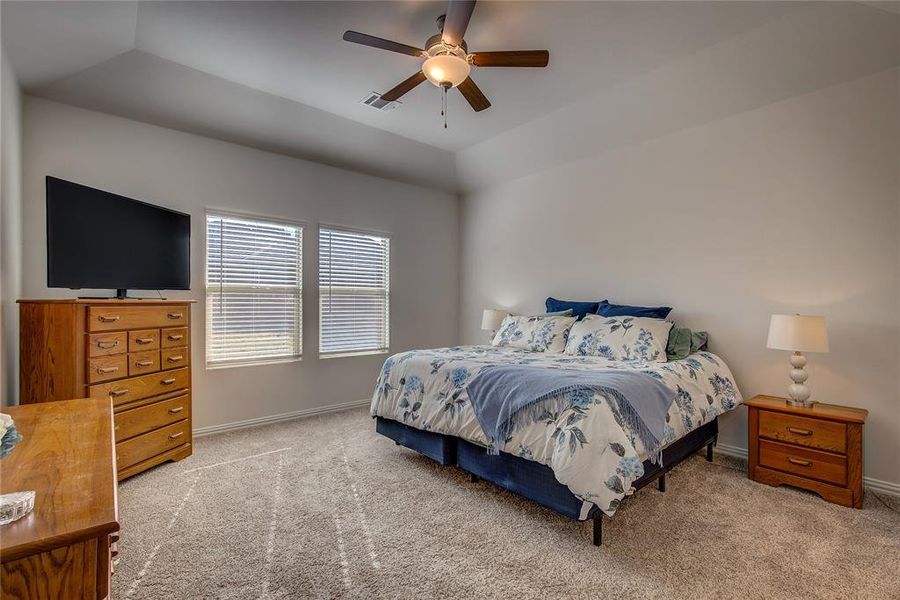 Bedroom with ceiling fan, light colored carpet, and vaulted ceiling