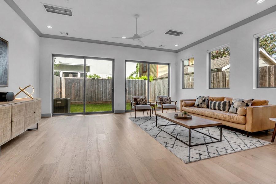 This closer view highlights the spacious living room, featuring wood flooring that continues seamlessly into the adjacent kitchen and dining areas for a cohesive flow throughout the main living spaces. (Virtually Staged Coffee Table)