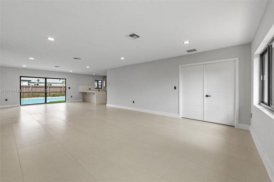 Open interior featuring large-format neutral tile flooring, recessed ceiling lighting, a built-in counter area, and sliding glass doors