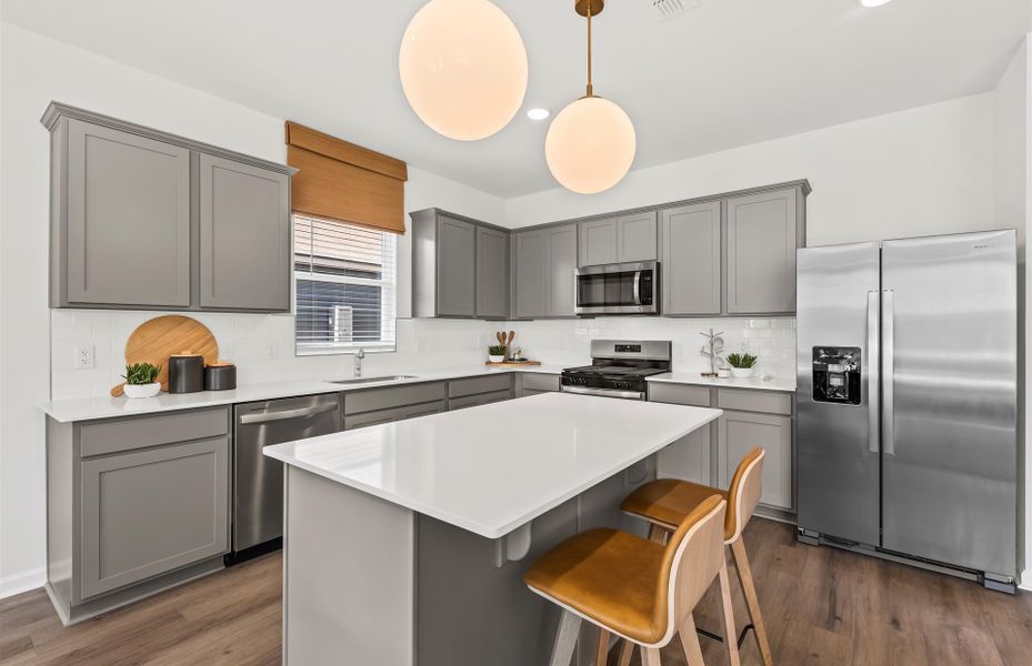 Kitchen with gray cabinets and pendant lights.