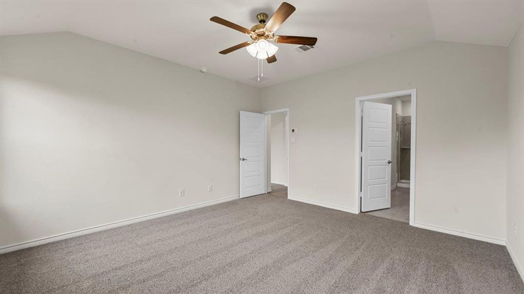 Spacious room featuring vaulted ceilings, light gray walls, gray carpeting, and a ceiling fan with integrated lighting