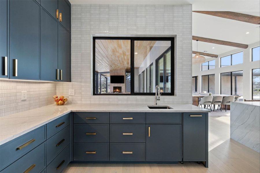 Bathroom featuring backsplash, plenty of natural light, light wood-type flooring, beam ceiling, and a towering ceiling