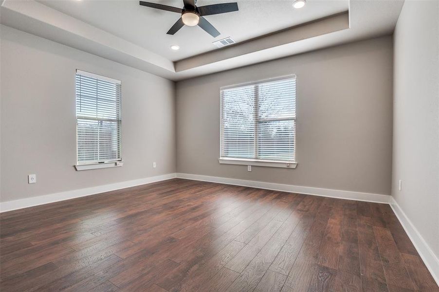 Spare room featuring a tray ceiling, dark wood-style flooring, plenty of natural light, recessed lighting, and a ceiling fan