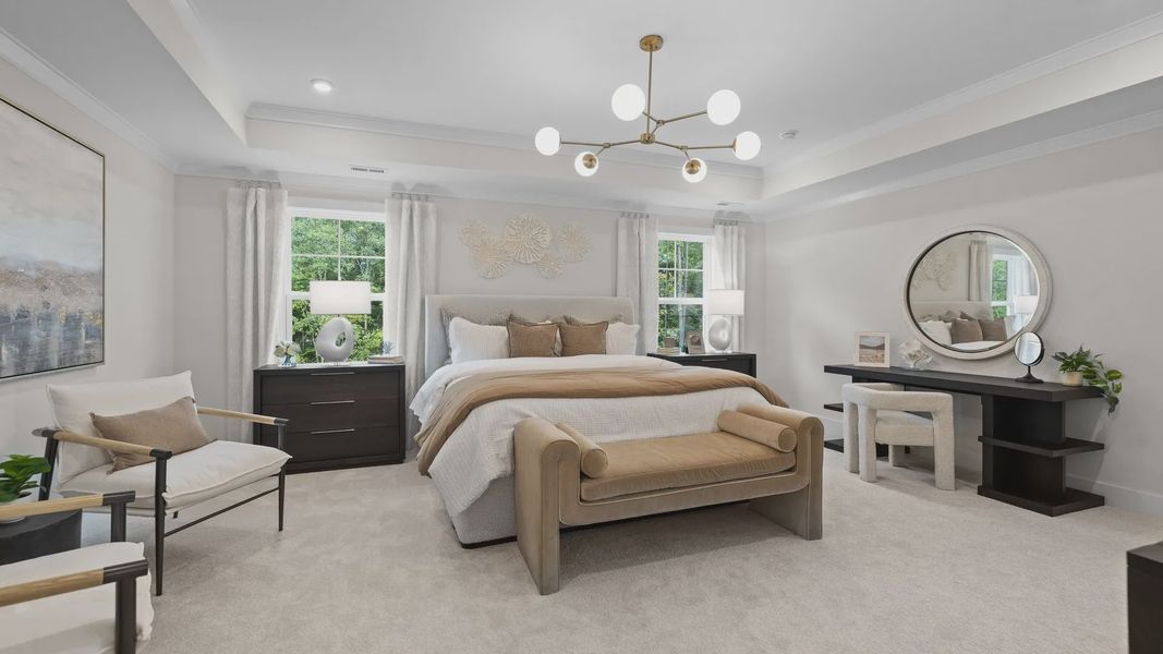 Grand primary bedroom with seating area, elevated tray ceiling, & large windows in the Jordan Design by DRB Homes in York, SC