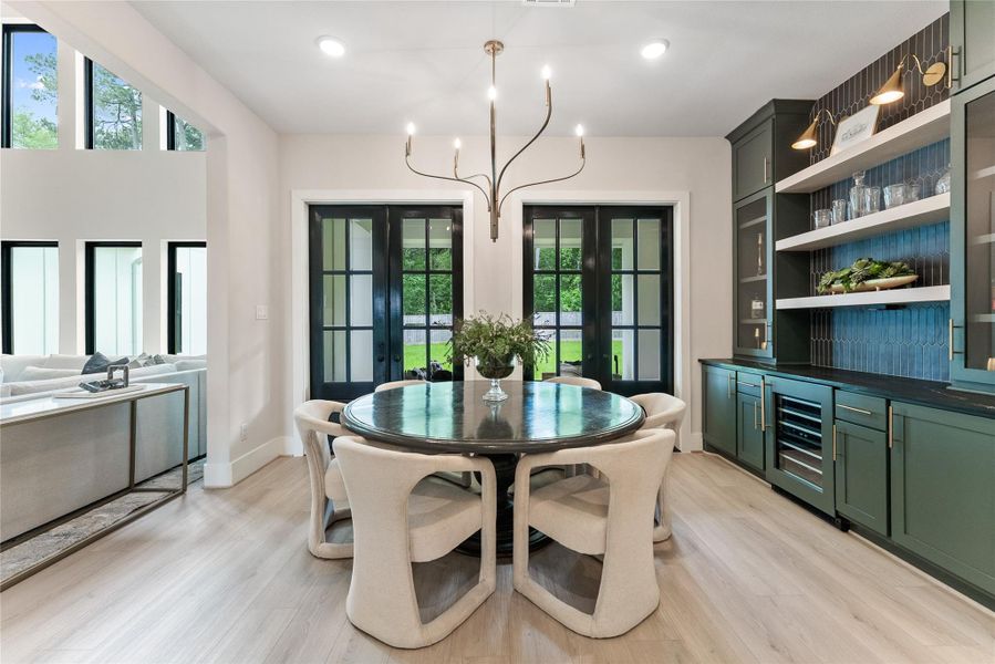 The dining area connects directly to the kitchen and outdoor living space through black framed doors. Designer lighting and built in cabinetry create a sophisticated setting for dinner parties and family meals.