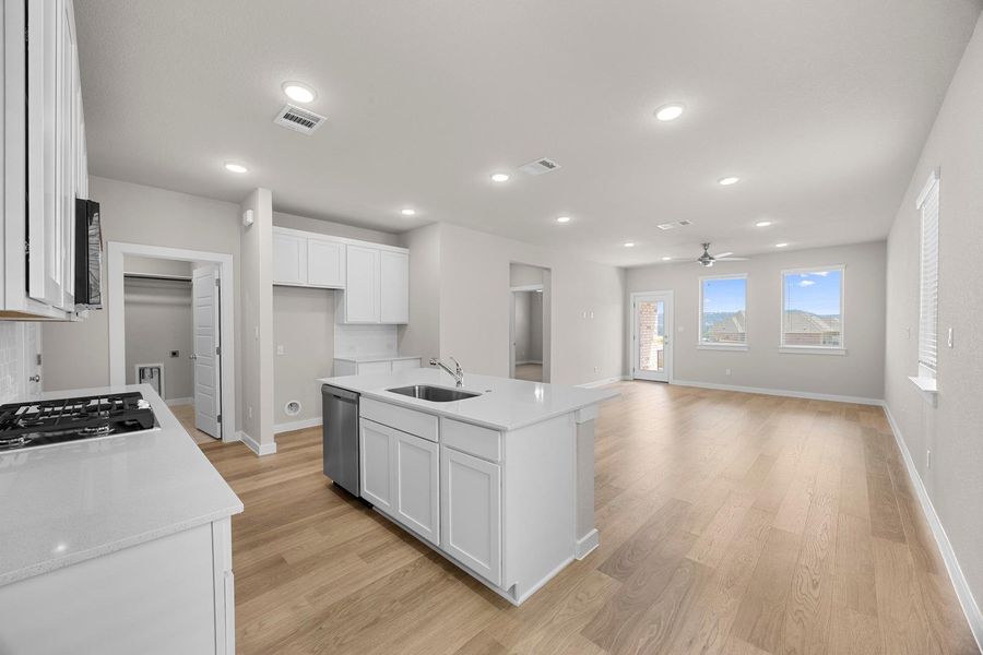 A well-lit, open-concept space features a modern kitchen island and light wood flooring throughout. A well-lit, open-concept space features a modern kitchen island and light wood flooring throughout.
