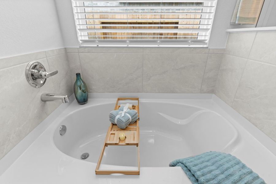 Soak your cares away in the inviting tub, perfectly positioned beneath a wide window that fills the space with natural light—creating your own serene spa-like sanctuary. **Image Representative of Plan Only and May Vary as Built**.