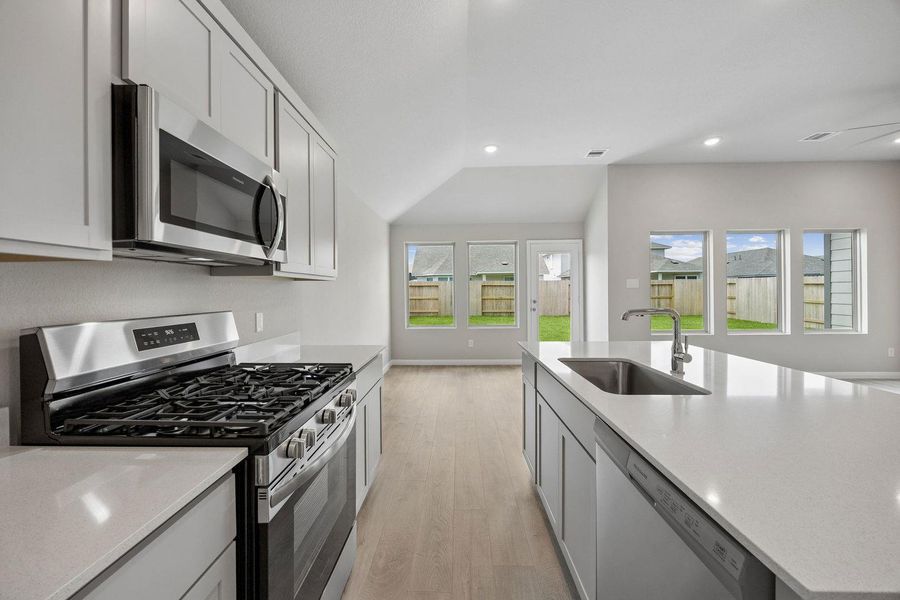 A contemporary kitchen space boasts sleek countertops and stainless steel appliances, opening to a sun-drenched yard.