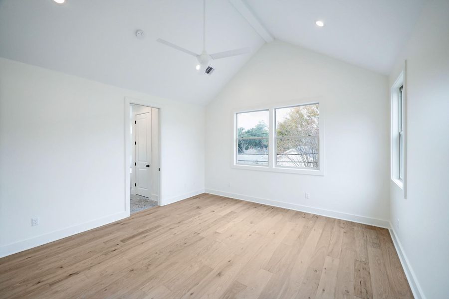 The smooth walls, neutral color palette and vaulted ceiling accentuate the open space found in the primary bedroom. Recessed lighting and large windows illuminate the space. *Previous Project*
