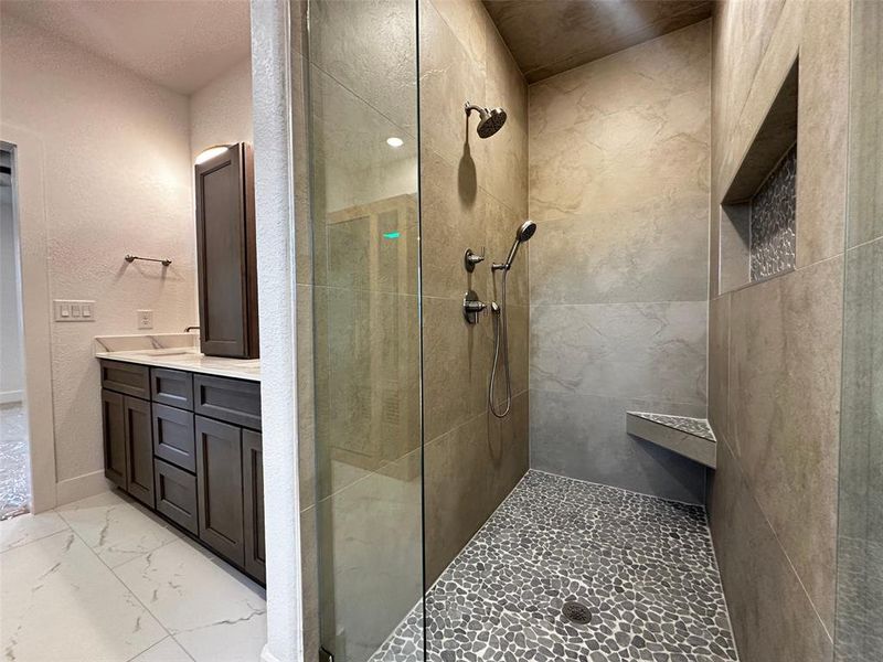 Bathroom with marble finish floor, vanity, and a tile shower
