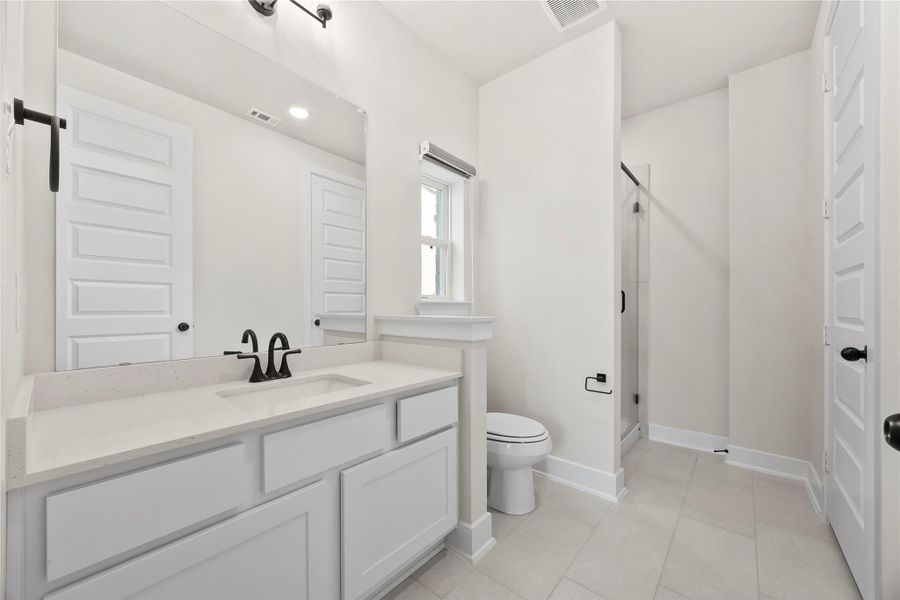 This bathroom features a clean, modern design with neutral tones. It includes a spacious vanity with black fixtures, a large mirror, a toilet, and a glass-enclosed shower. The room is well-lit and has a minimalistic aesthetic. This bathroom features a clean, modern design with neutral tones. It includes a spacious vanity with black fixtures, a large mirror, a toilet, and a glass-enclosed shower. The room is well-lit and has a minimalistic aesthetic.