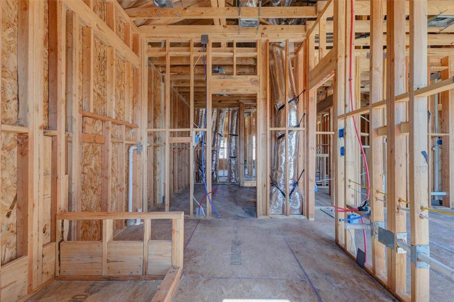 Interior hallway and room transition view showing exposed framing, ductwork, plumbing, and electrical rough-ins throughout the upper level. This perspective highlights the home’s internal flow and gives buyers a useful look at how bedrooms, baths, and mechanical systems are organized within the floor plan. Interior hallway and room transition view showing exposed framing, ductwork, plumbing, and electrical rough-ins throughout the upper level. This perspective highlights the home’s internal flow and gives buyers a useful look at how bedrooms, baths, and mechanical systems are organized within the floor plan.