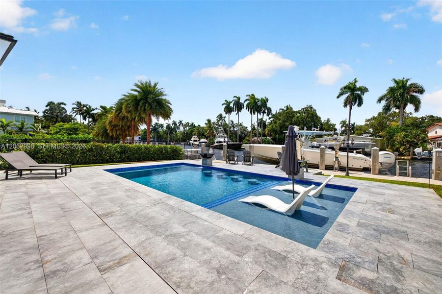 Salt chlorinated pool w/ water features, LED color changing light, sun shelf with umbrella hole and in water stools. Stone decking surrounds the pool