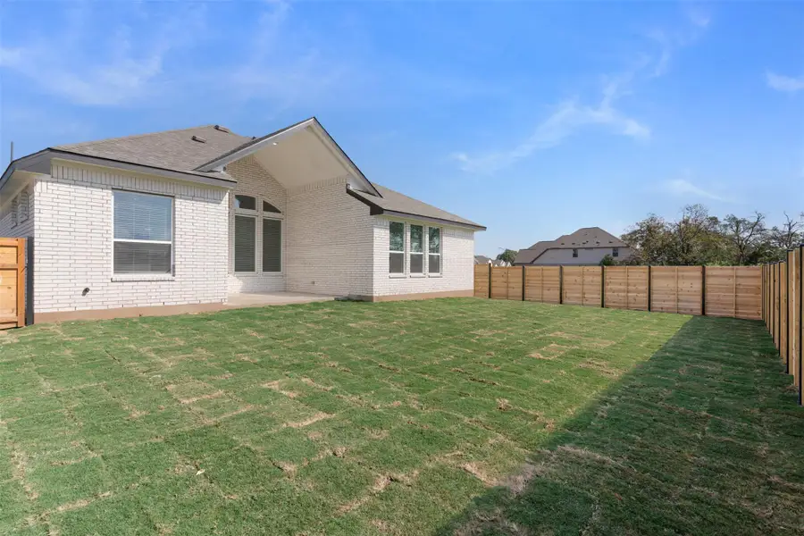 Rear view of house with a fenced backyard, a patio, and brick siding