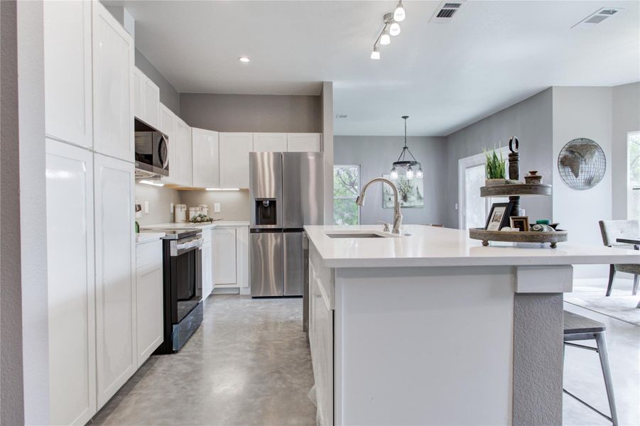 Kitchen with stainless steel fridge with ice dispenser, black electric range, a sink, concrete floors, and light countertops