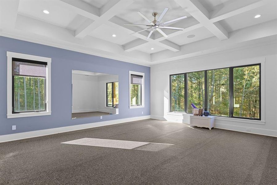 Carpeted spare room featuring coffered ceiling, radiator heating unit, healthy amount of natural light, beam ceiling, and recessed lighting