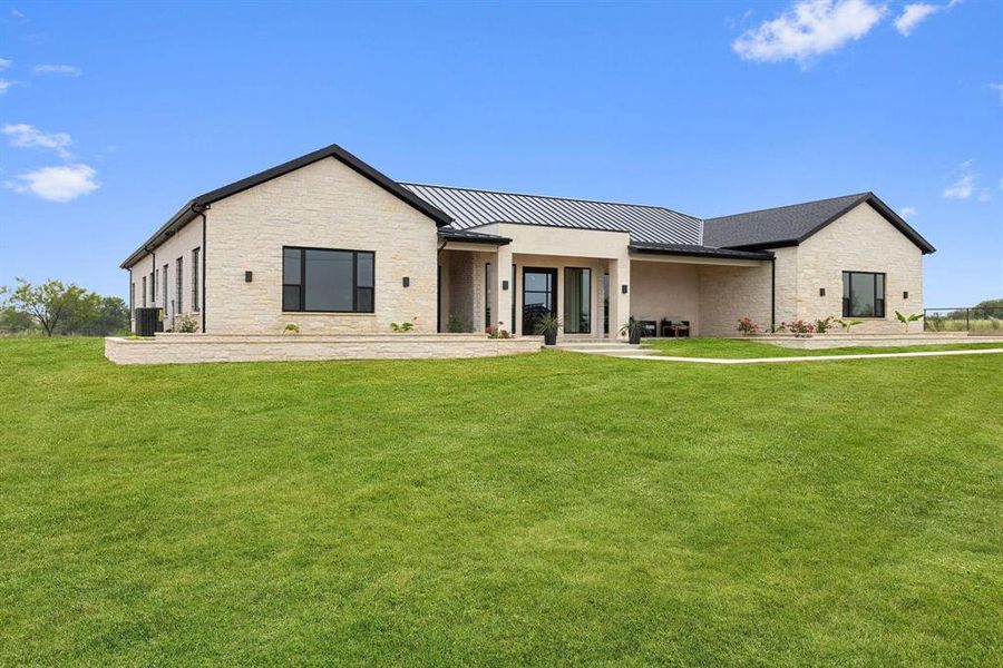 View of front of home featuring stone siding, a
standing seam roof, a porch, a metal roof, and a
front lawn View of front of home featuring stone siding, a
standing seam roof, a porch, a metal roof, and a
front lawn