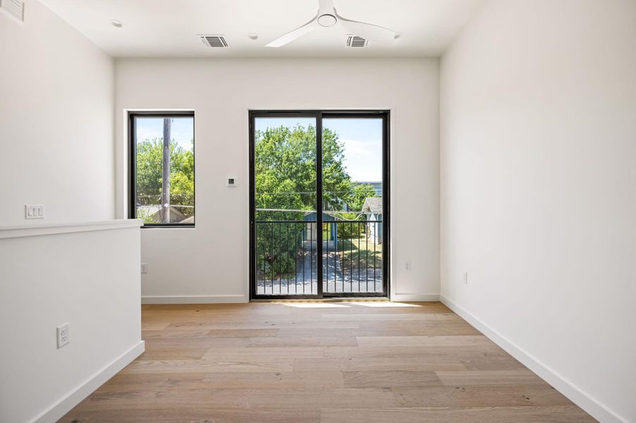 Gleaming wood floors anchor this minimalist room showcasing a glass door to a private balcony.