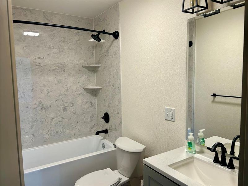 Bathroom featuring a textured wall, shower / tub combination, and vanity