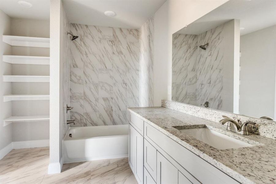 Bathroom with a combined bath / shower with marble appearance, light marble finish flooring, and vanity