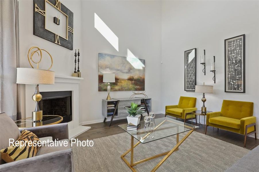 Two-story living area featuring a prominent fireplace with a white mantel, dark wood-finish flooring, and high ceilings