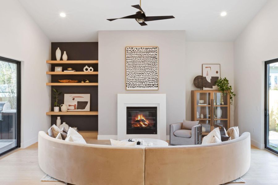 Living room featuring light wood finished floors, baseboards, recessed lighting, a glass covered fireplace, and a ceiling fan