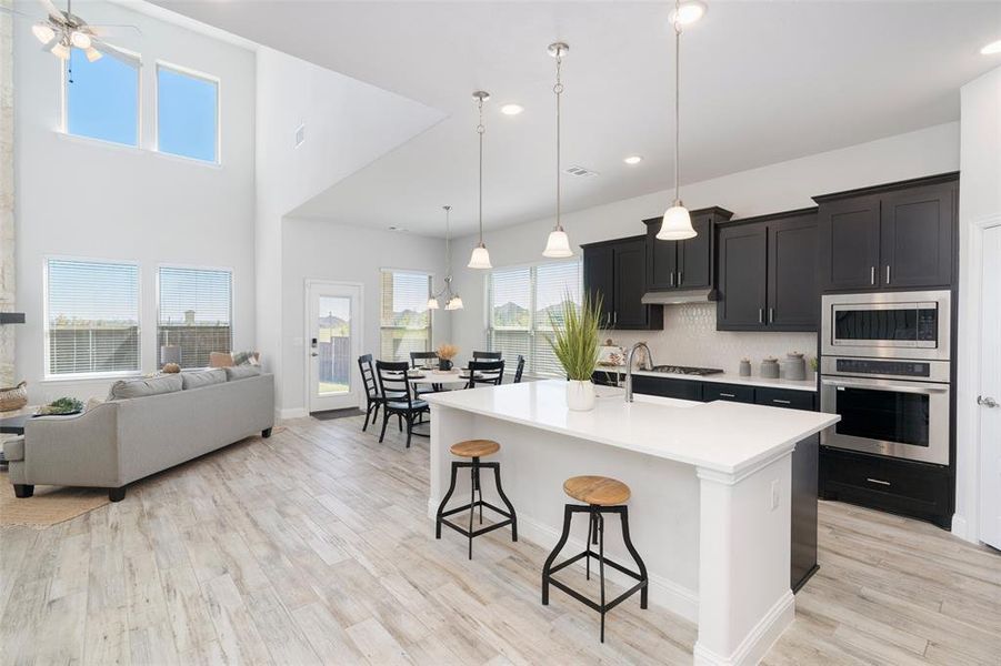 Kitchen with a healthy amount of sunlight, stainless steel appliances, a breakfast bar, and a kitchen island with sink