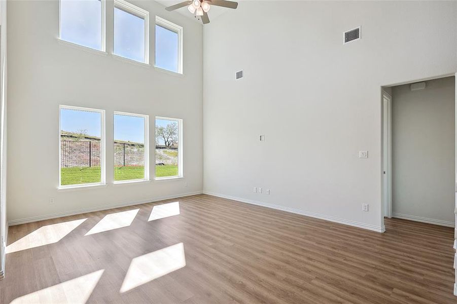 Unfurnished living room with a high ceiling, wood-type flooring, and ceiling fan