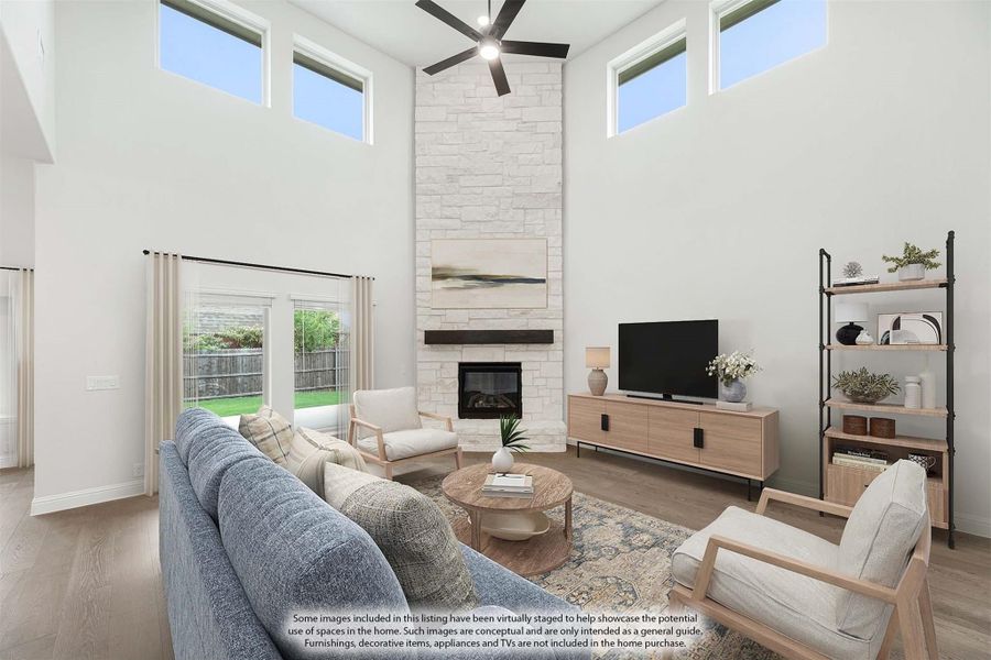 Living room with two-story ceiling, stone fireplace, ceiling fan, and hardwood floors Living room with two-story ceiling, stone fireplace, ceiling fan, and hardwood floors