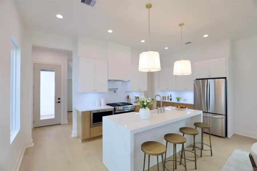 A 3cm waterfall island featuring a continuous quartz surface that elegantly wraps over the edges. The back of the island is fully finished in quartz, highlighting the stone’s natural veining and creating a seamless, high-end aesthetic that enhances the overall kitchen design.