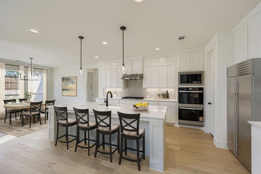 Virtually staged photo - Kitchen featuring a breakfast bar area, built in appliances, and white cabinetry