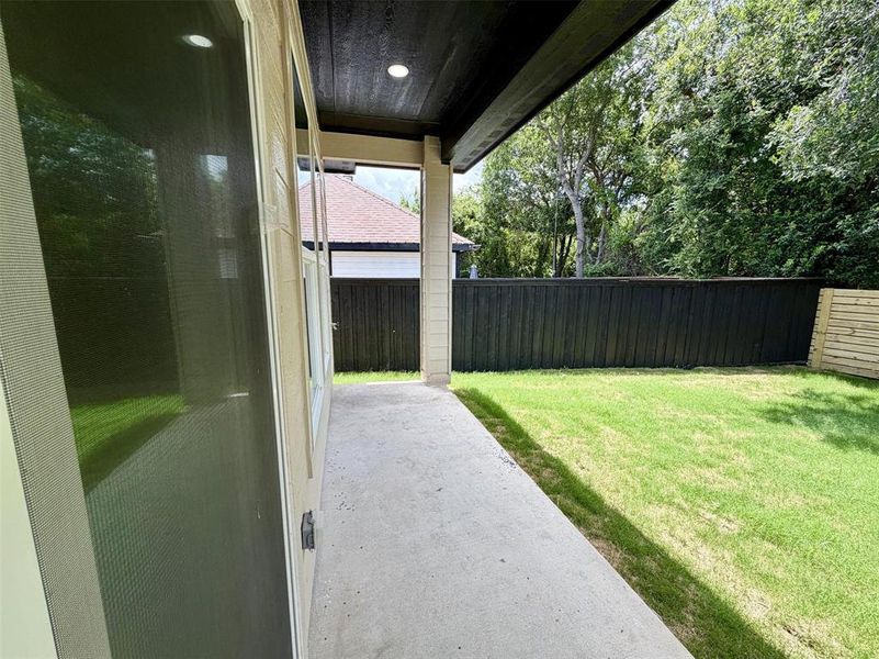 Private outdoor space featuring a concrete patio, verdant lawn, and a dark-stained wood fence Private outdoor space featuring a concrete patio, verdant lawn, and a dark-stained wood fence