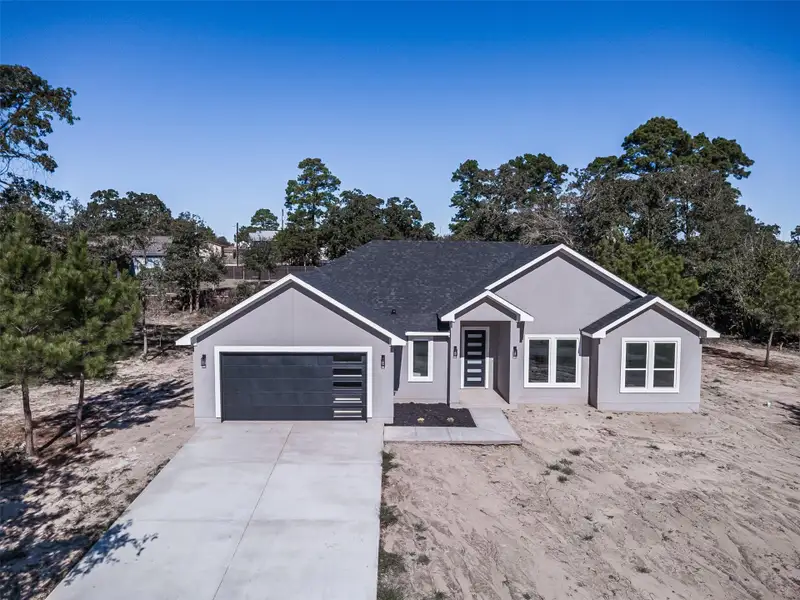 View of front facade with driveway, an attached garage, and a shingled roof