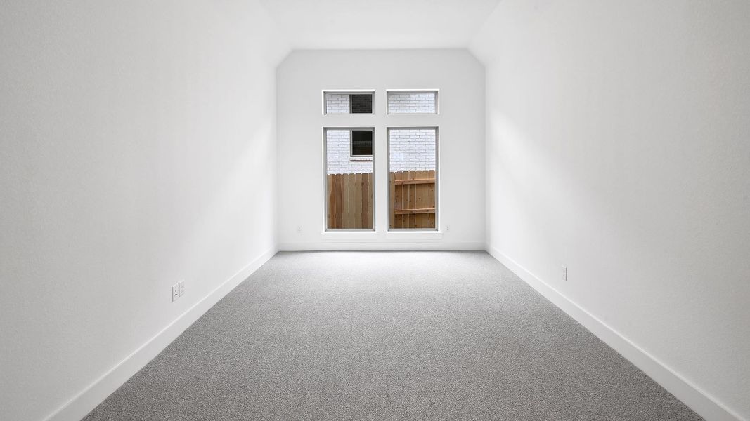 Carpeted empty room with baseboards and vaulted ceiling Carpeted empty room with baseboards and vaulted ceiling