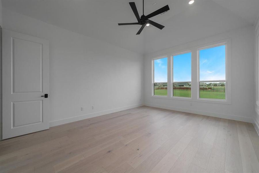 Empty room with light wood-type flooring, ceiling fan, and vaulted ceiling