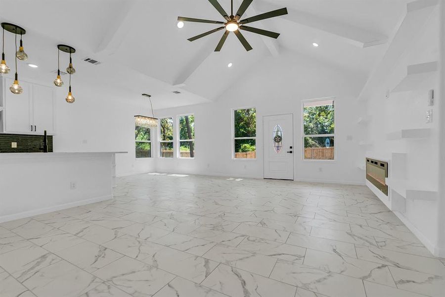 Unfurnished living room with light tile patterned floors, beam ceiling, and ceiling fan