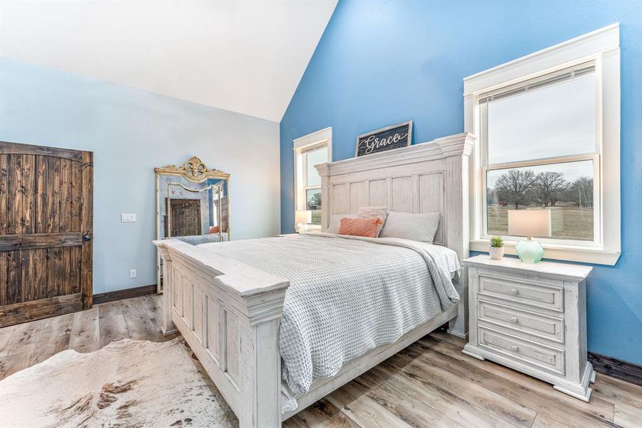 Bedroom featuring high vaulted ceiling and wood finished floors