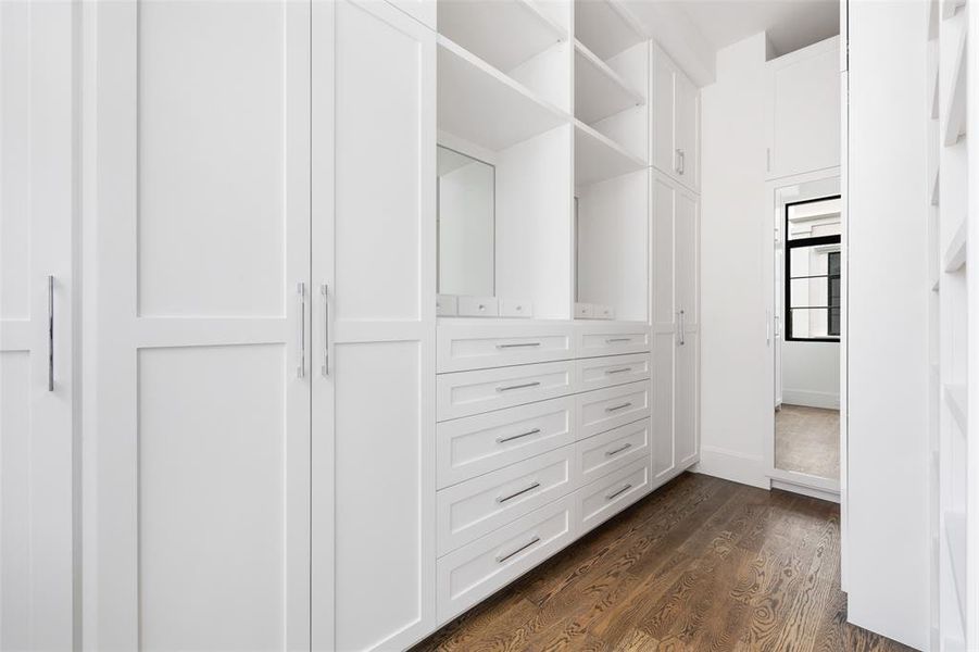 The spacious walk-in closet features elevated features such as furniture style cabinetry, adjustable shelves, a vanity area with specialized accessory storage, valet rods, and more. Image from previously completed home in the community.